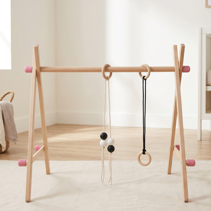Wooden baby gym with hanging toys on a light wooden floor.