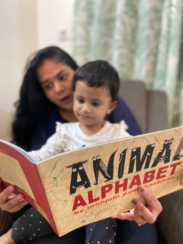Woman and child reading an 'Animal Alphabet' book together.