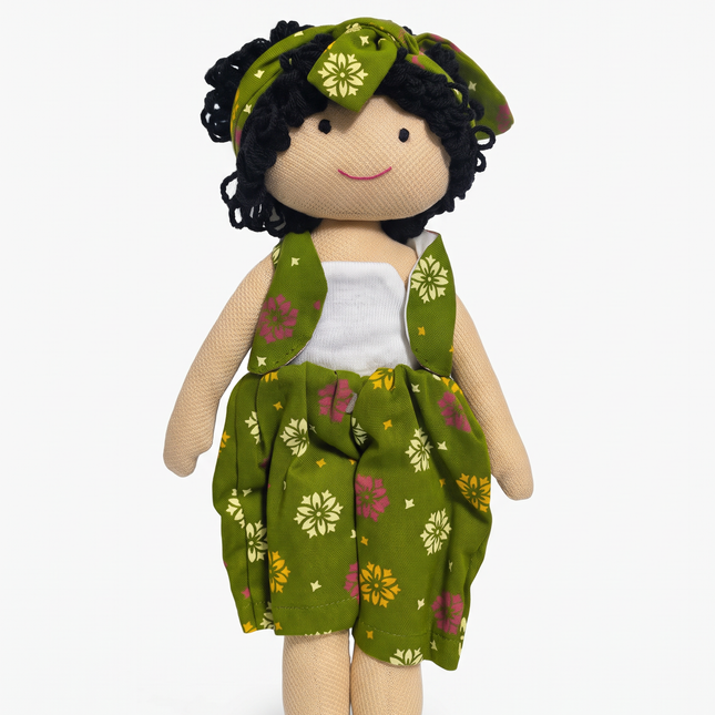 A handmade fabric doll with curly black yarn hair, wearing a green floral dress and matching headband over a white top, set against a plain white background.