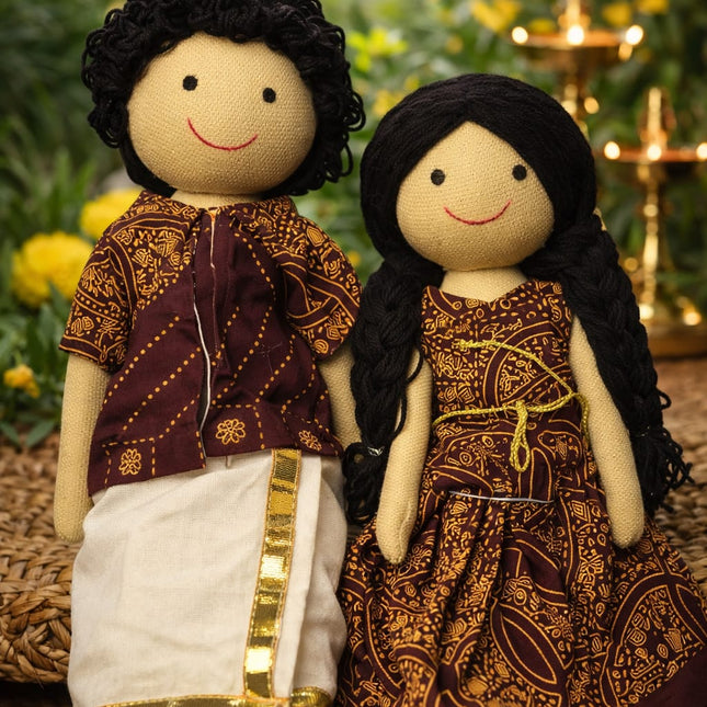 Two dolls dressed in traditional attire with a blurred natural background