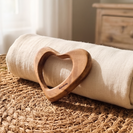 Wooden Teether Heart Shape object on a rolled-up fabric with a blurred background